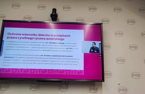 Prezentacja na ekranie w sali konferencyjnej PAP dotycząca ochrony wizerunku dziecka w prawie cywilnym i prawie autorskim. Slajd zawiera tytuł oraz informacje o art. 23 Kodeksu cywilnego i art. 81 ustawy o prawie autorskim, opisujące zasady ochrony wizerunku, zakaz nieuprawnionego utrwalania i rozpowszechniania oraz konieczność zgody przedstawiciela ustawowego.